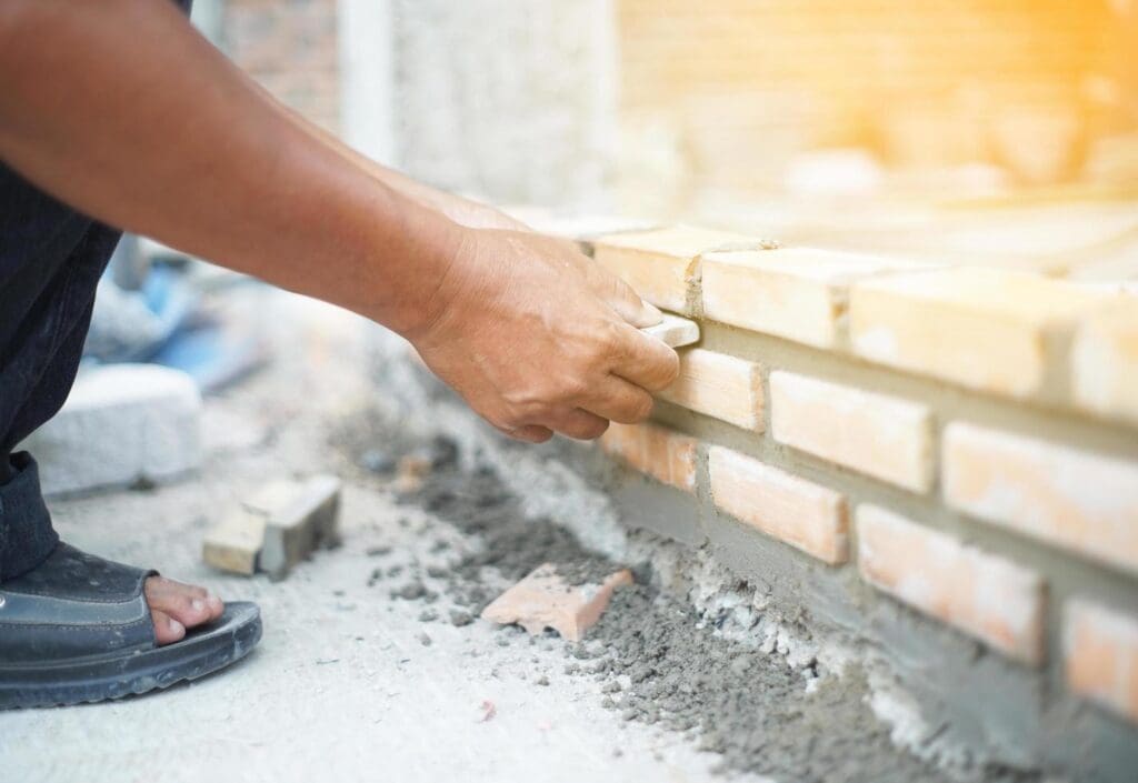 Bricklayer placing brick in mortar.