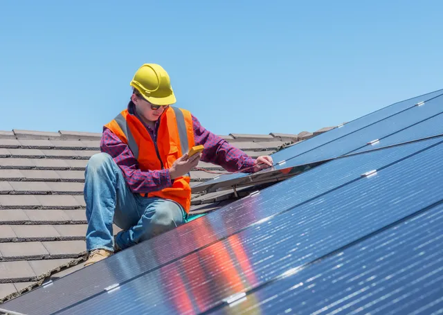 Technician inspecting solar panel array.