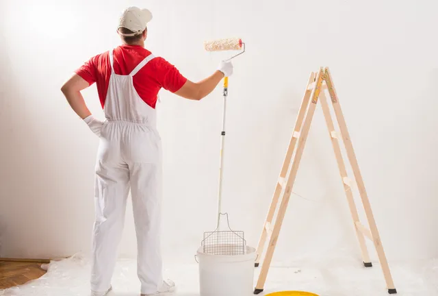 Painter using roller to paint wall.